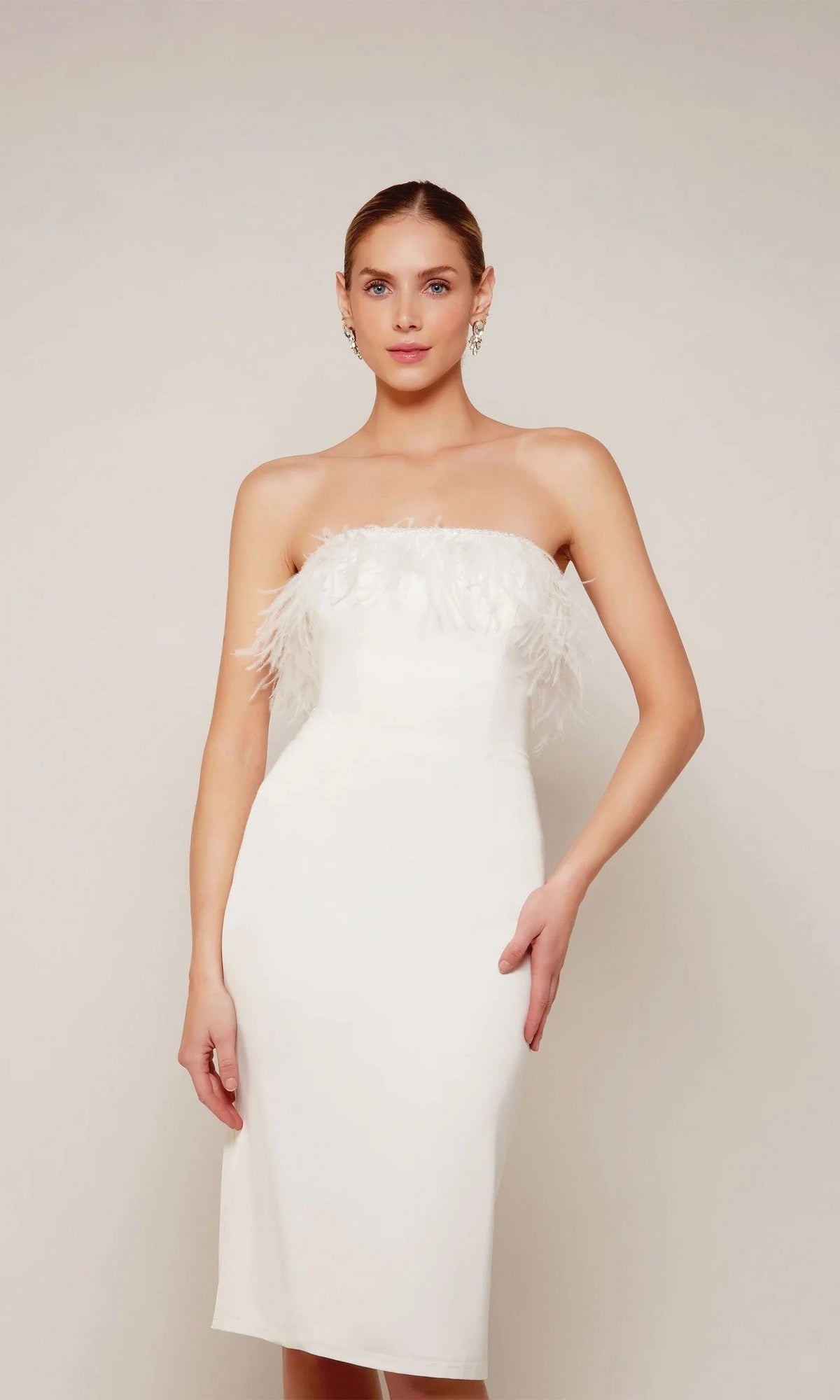 A woman stands against a plain light background wearing the Alyce 70028 knee-length semi-formal dress, featuring a strapless design and white feather trim detailing around the top.